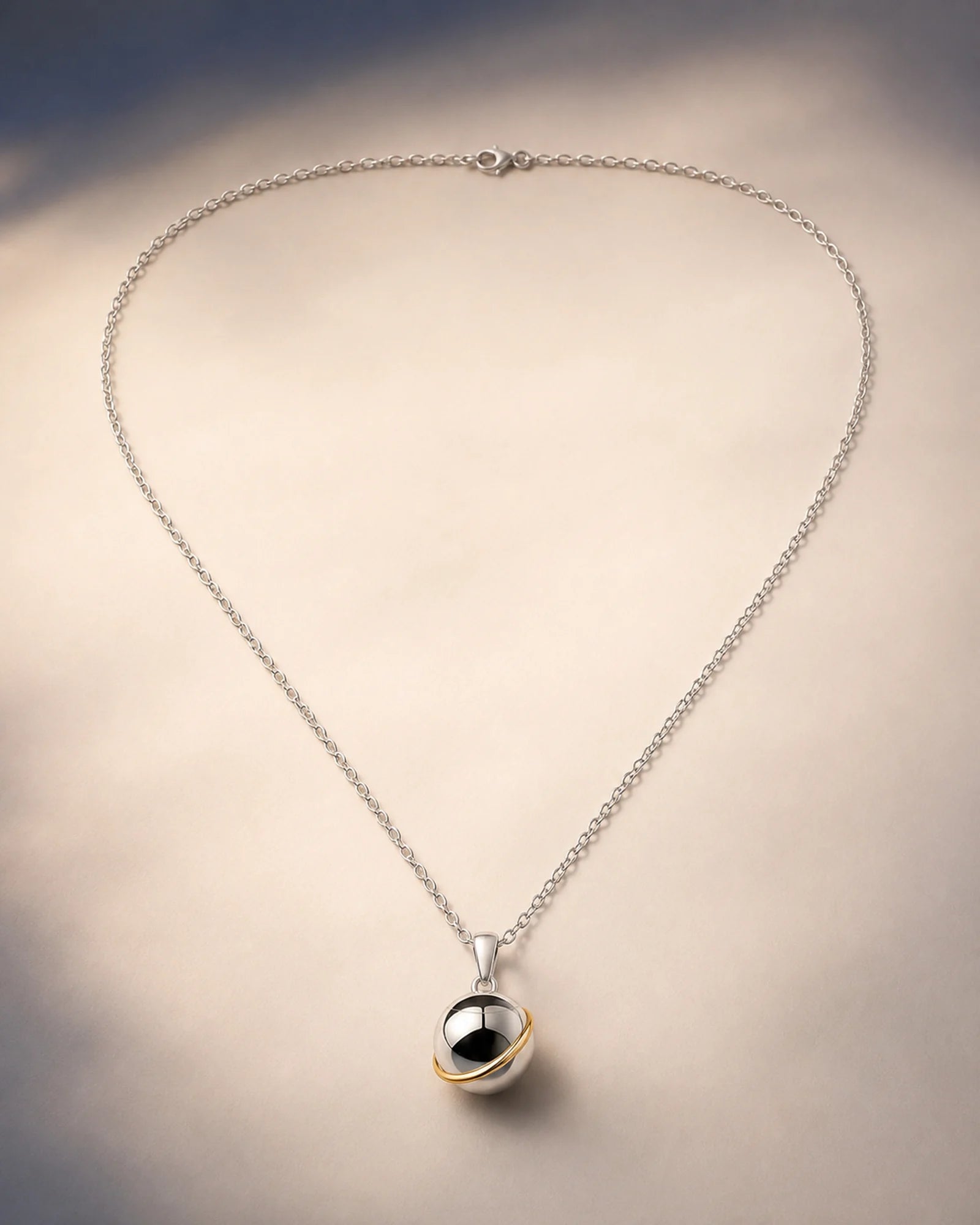 Silver round keepsake necklace with a warm-gold orbit detail