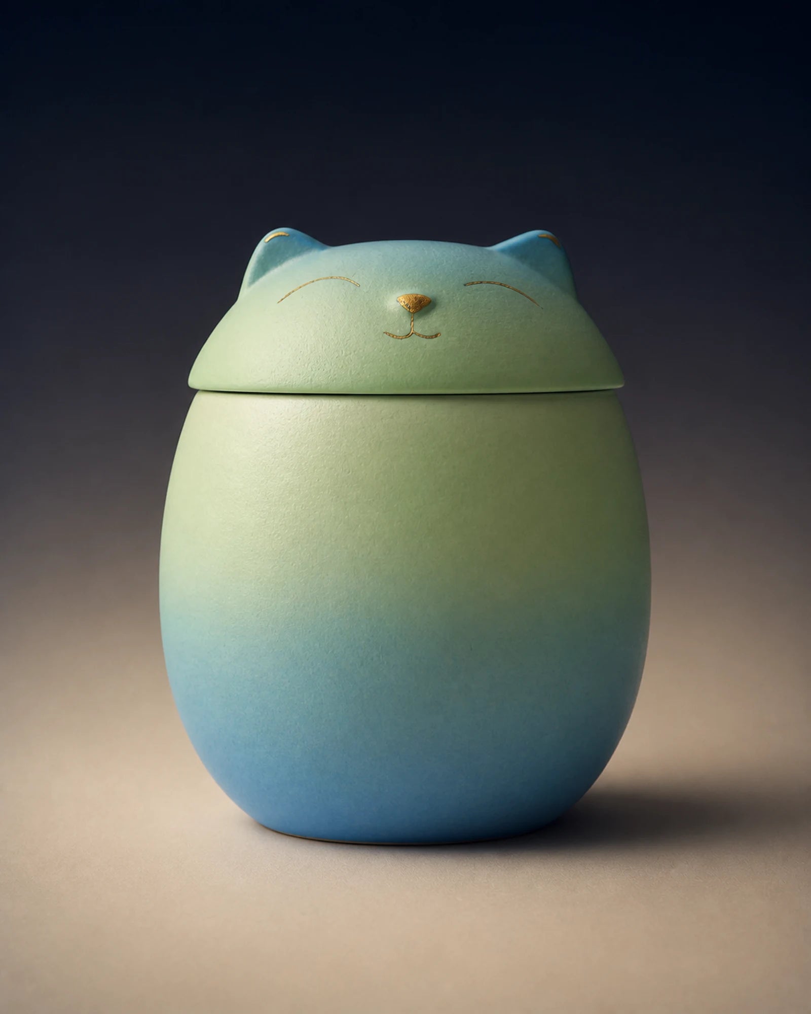 Blue-green cat-shaped memorial urn with restrained gold facial details