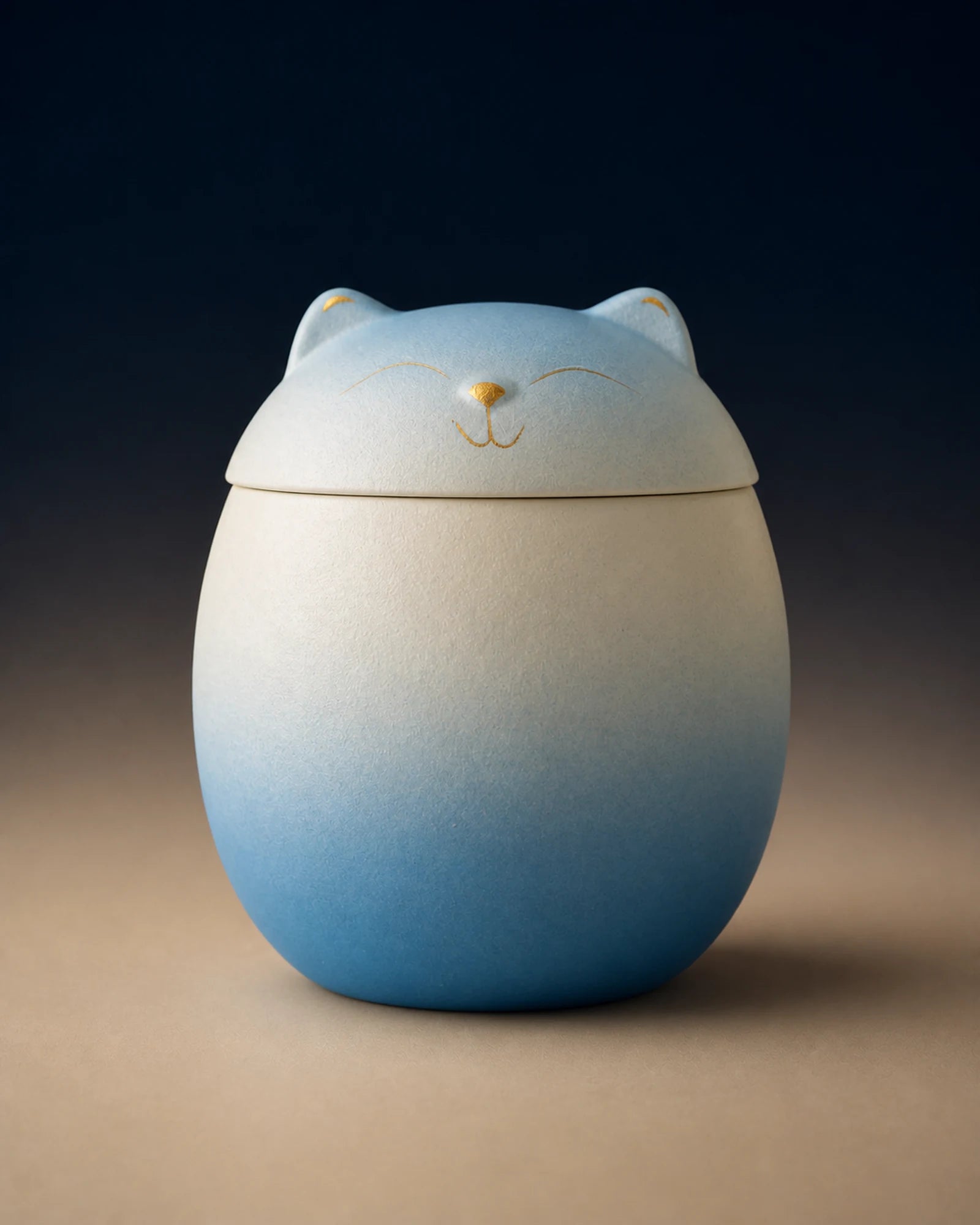 Blue-white cat-shaped memorial urn with restrained gold facial details