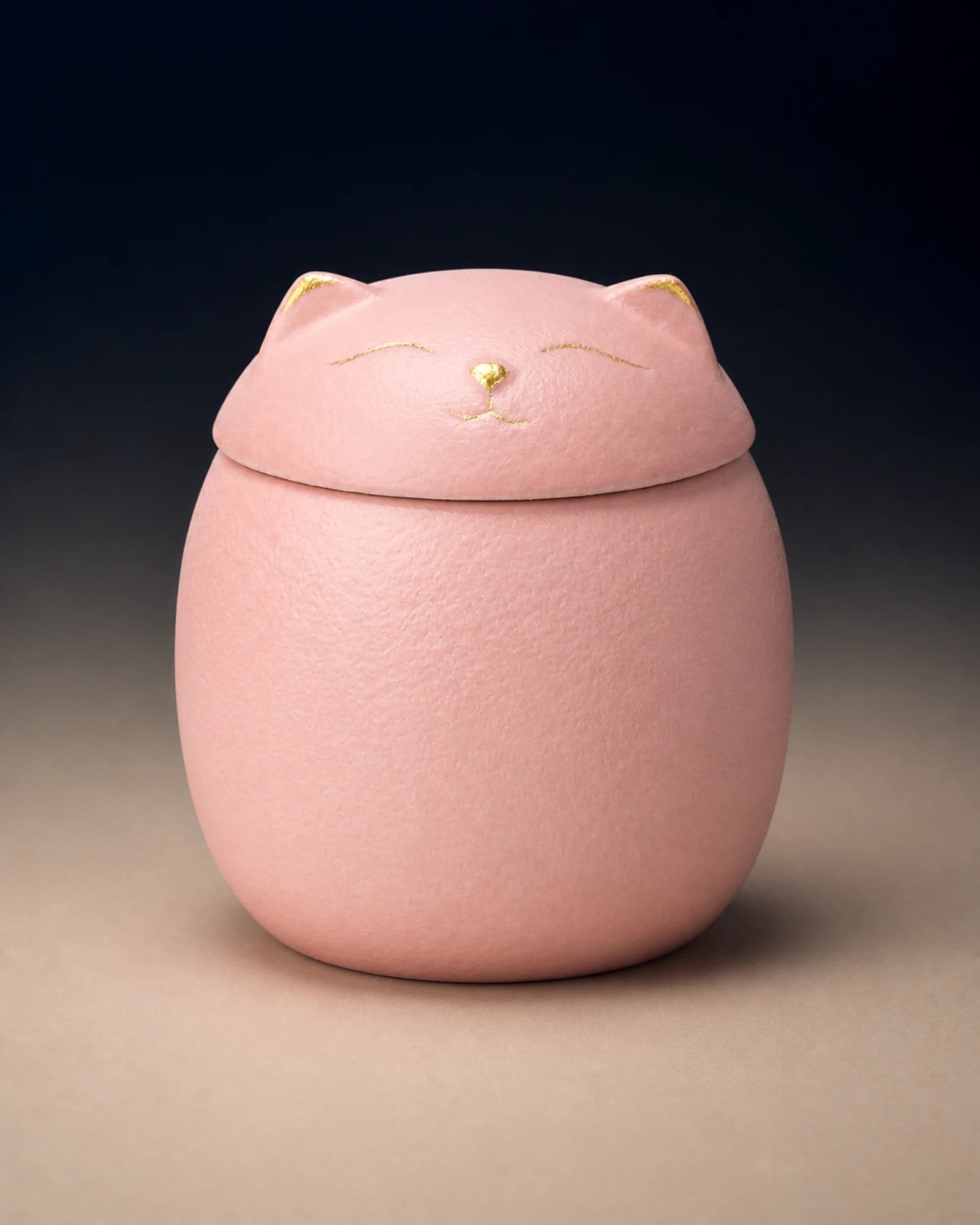 Pink cat-shaped memorial urn with restrained gold facial details