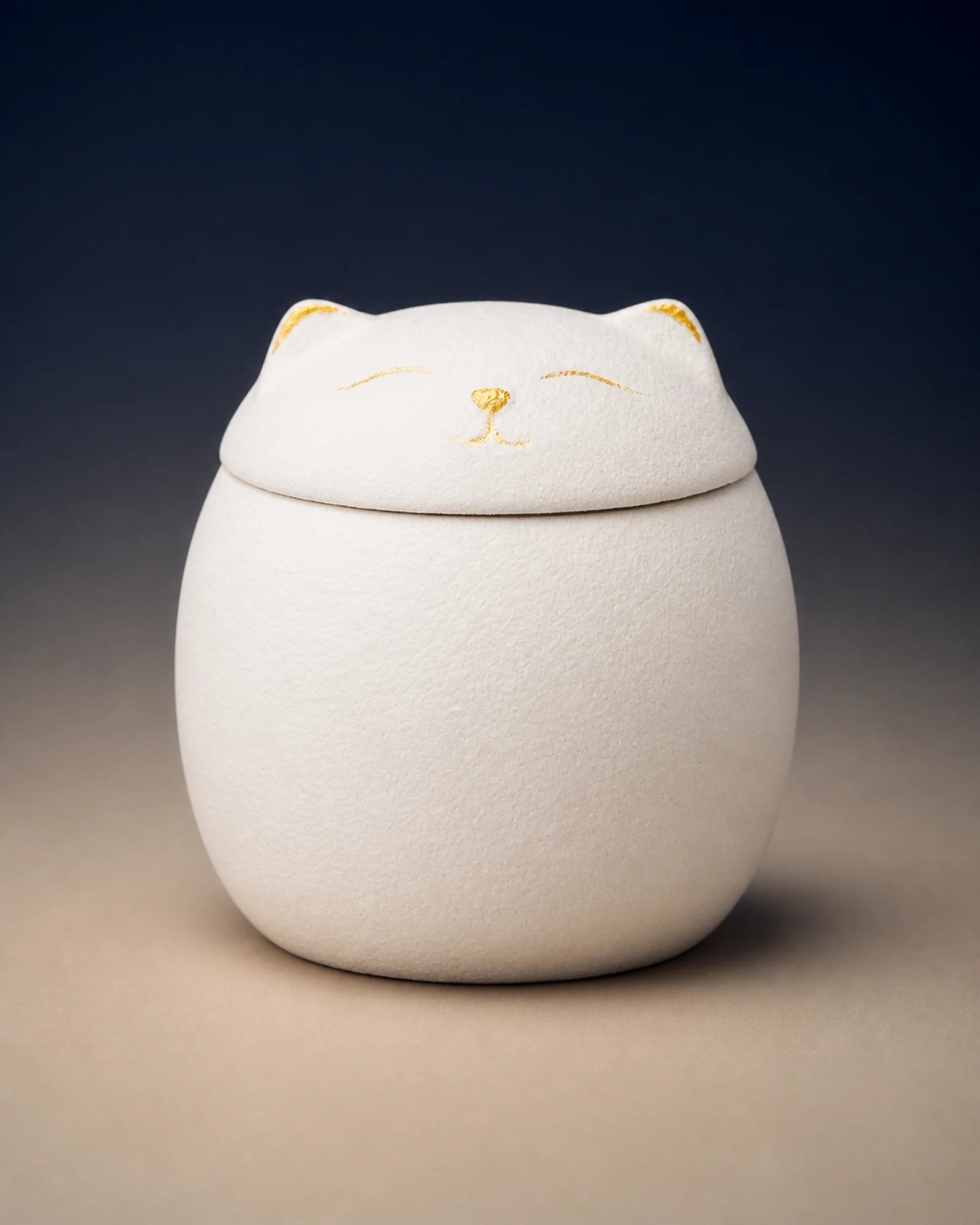 White cat-shaped memorial urn with restrained gold facial details