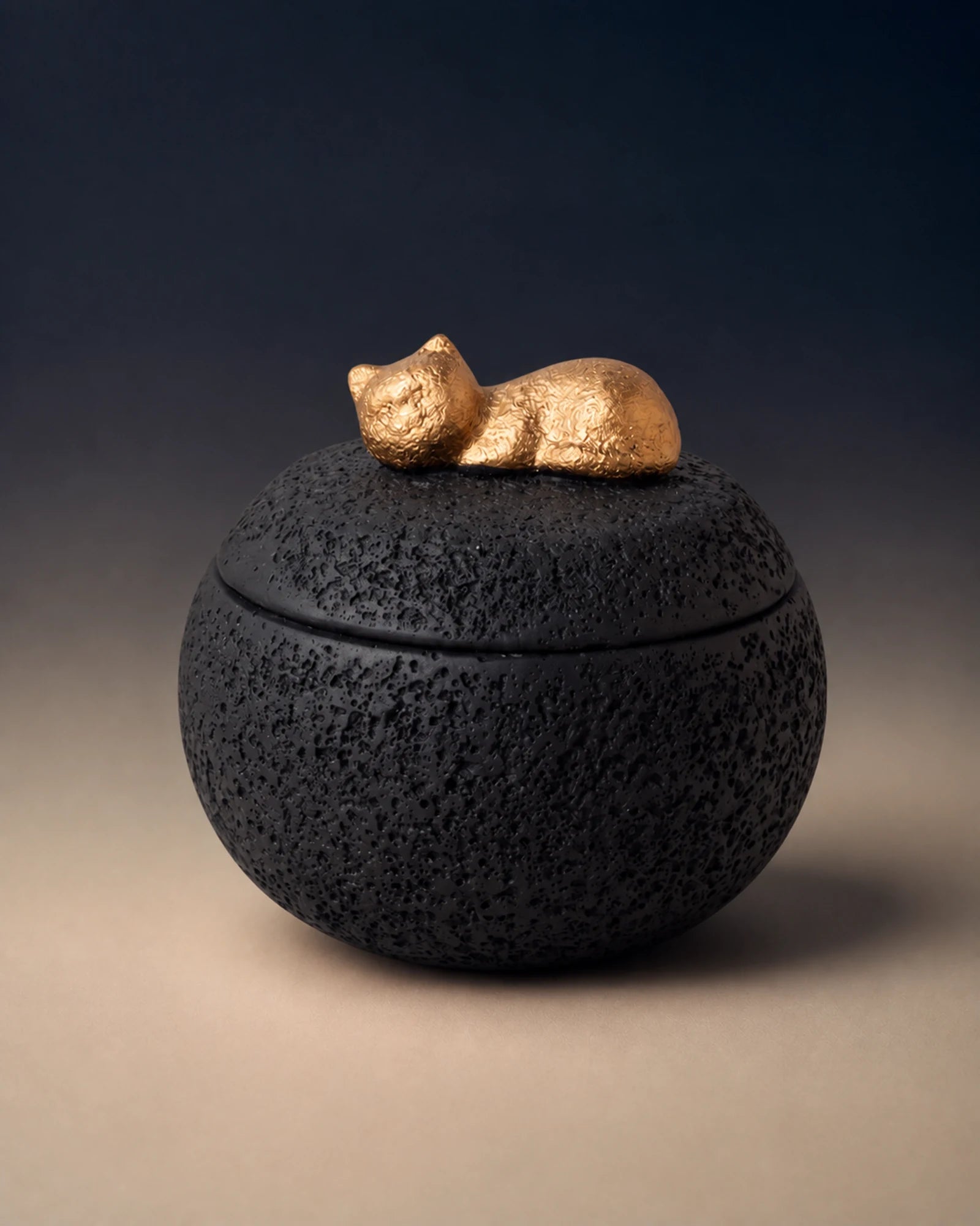 Black cement-textured memorial urn topped with a small gold sleeping cat