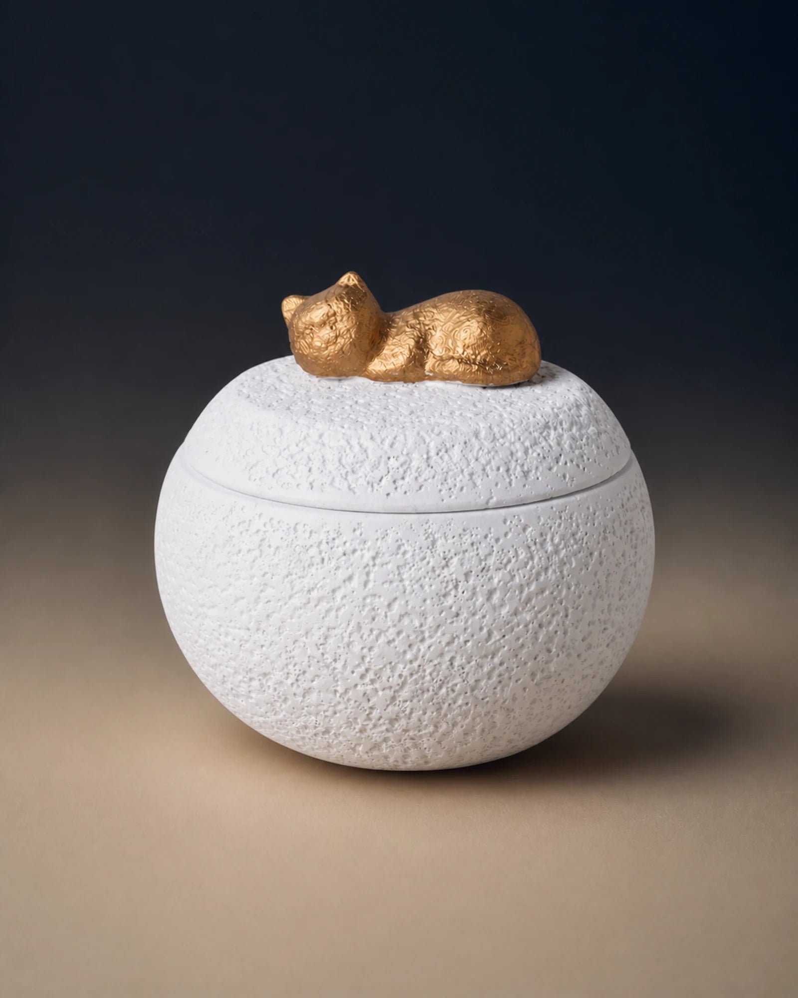 White cement-textured memorial urn topped with a small gold sleeping cat