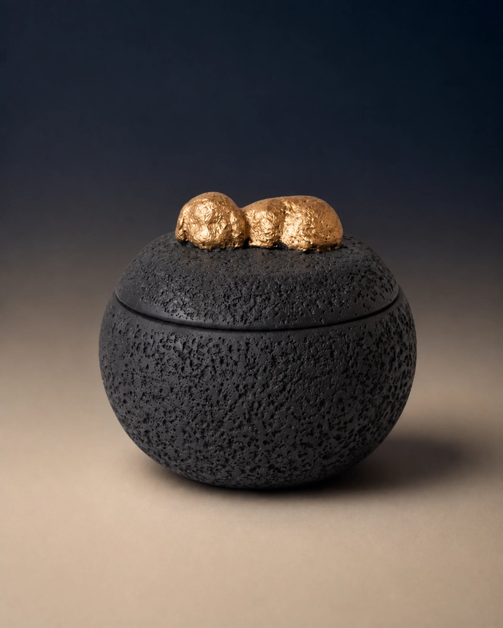 Black cement-textured memorial urn topped with a small gold sleeping dog