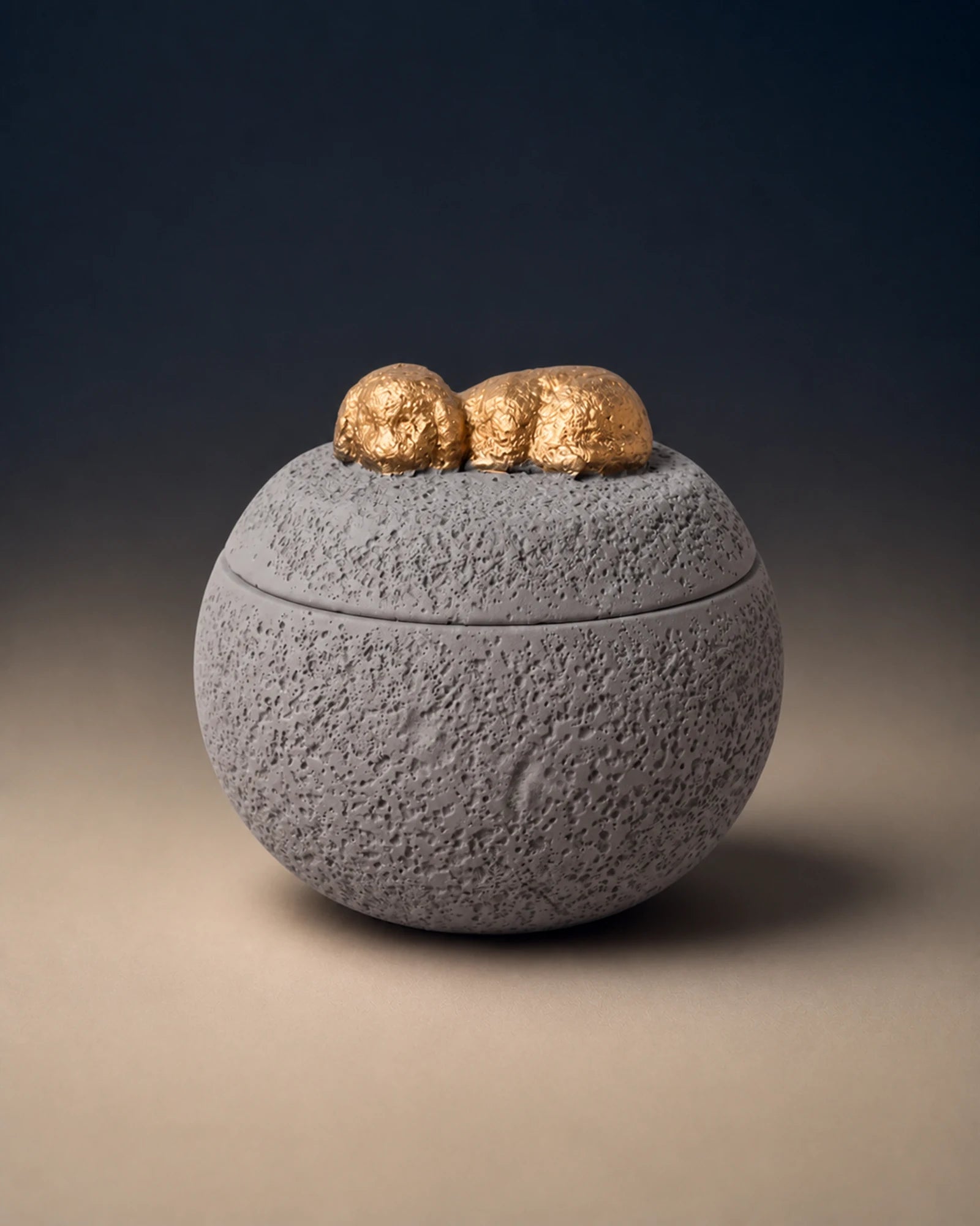 Gray cement-textured memorial urn topped with a small gold sleeping dog
