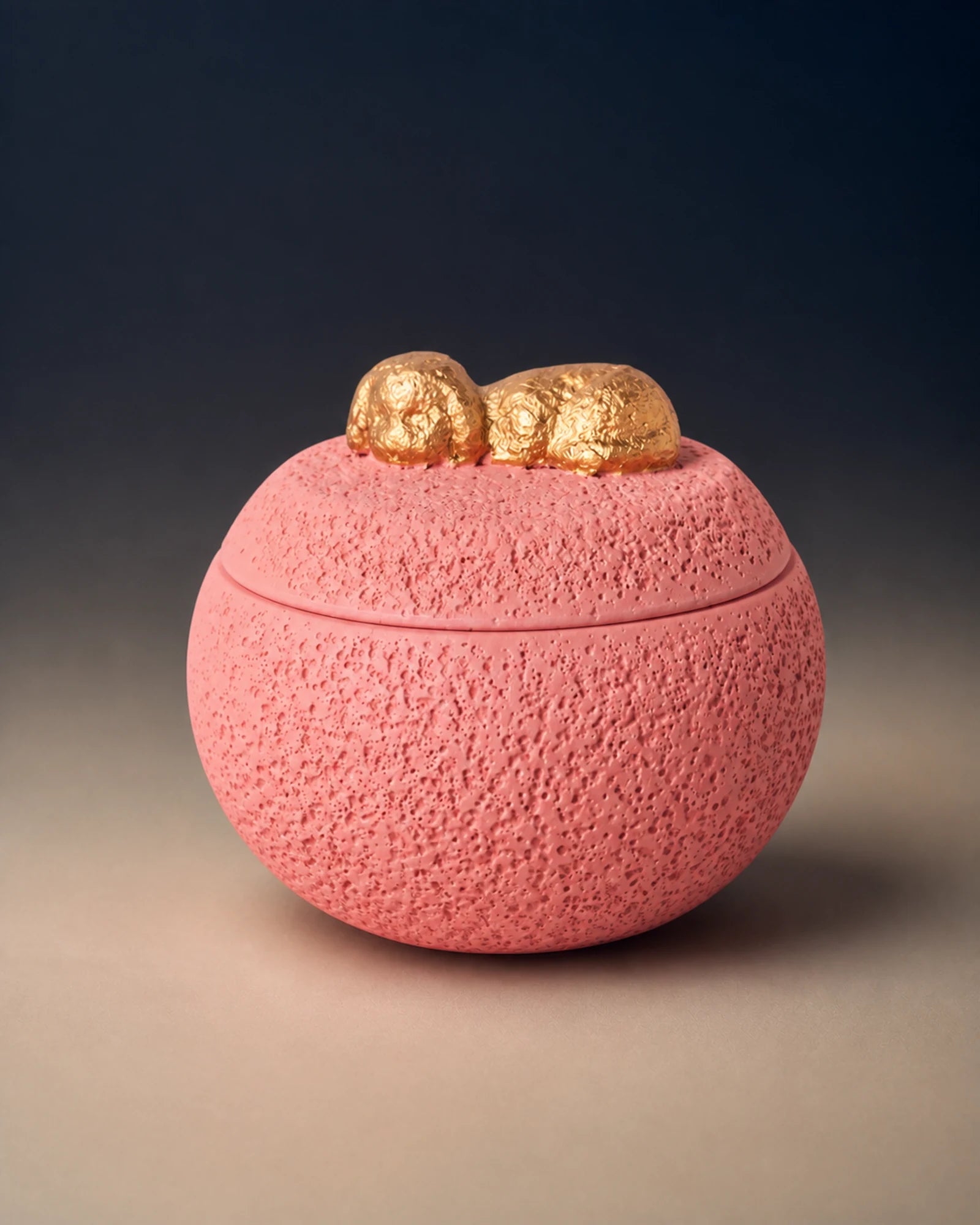 Pink cement-textured memorial urn topped with a small gold sleeping dog